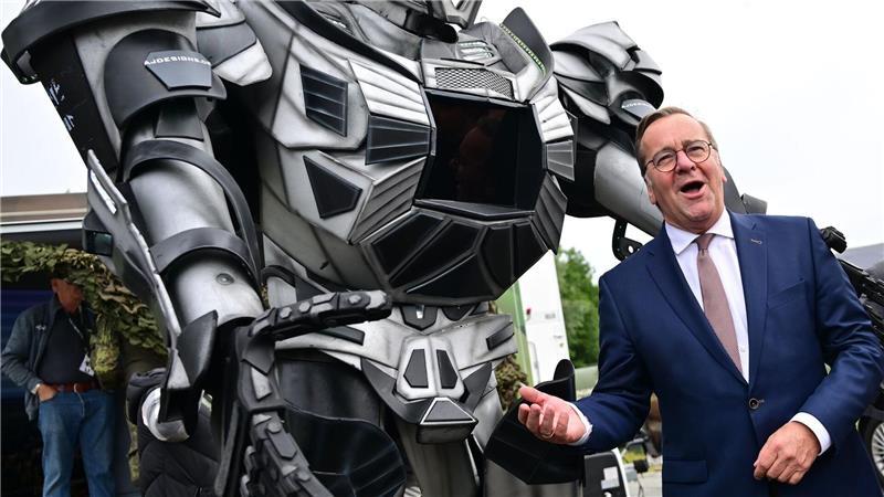 Verteidigungsminister Pistorius scherzt neben einer Transformer-Figur bei der ILA 2026 in Berlin.