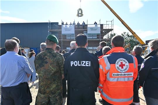 Vertreter von Polizei, Bundeswehr, Feuerwehr und Hilfsorganisationen wie DRK und Feuerwehr verfolgen die Reden von Lindemann-Geschäftsführer Friedrich Witt und Landrat Kai Seefried (CDU) beim Richtfest des Kreis-Katastrophenschutzzentrums i