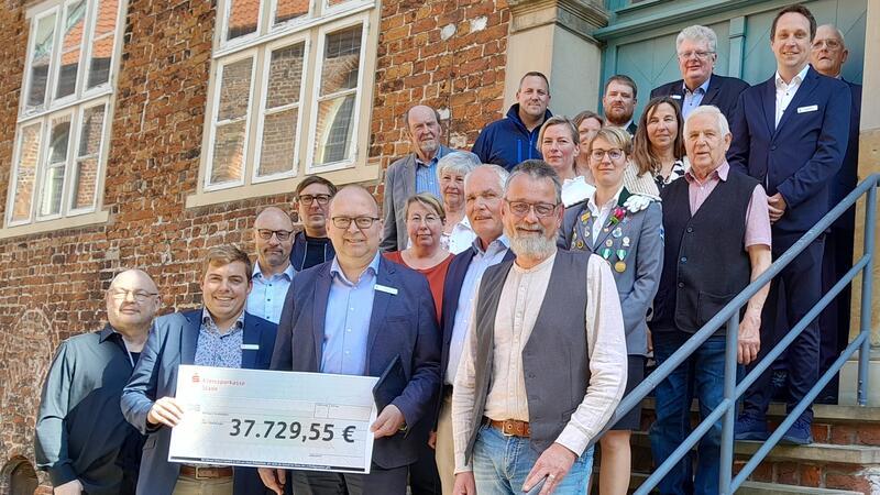 Kreissparkasse gibt Geld für Ruderboote, Schwimmkurse und Gewehre Vertreterinnen und Vertreter von Stadtverwaltung, Kreissparkasse, Politik und Institutionen vor dem historischen Rathaus in Stade
