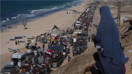 Vertriebene Palästinenser fahren auf Lastwagen die Küstenstraße in der Nähe von Wadi Gaza entlang und schwenken ägyptische und palästinensische Fahnen.