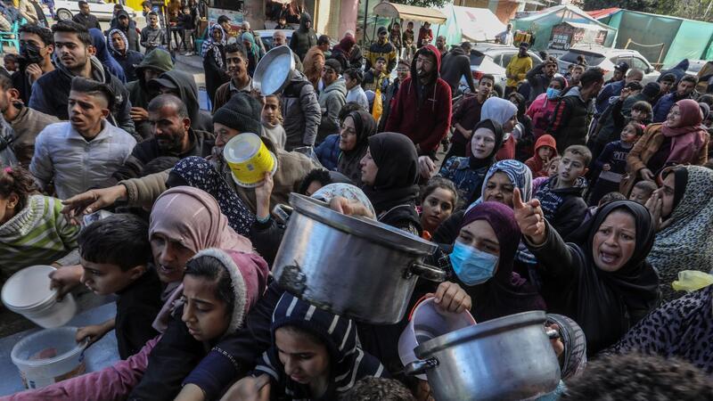 Vertriebene Palästinenser warten in Rafah, im Süden des Gazastreifens, auf Lebensmittel, die von palästinensischen Freiwilligen verteilt werden.