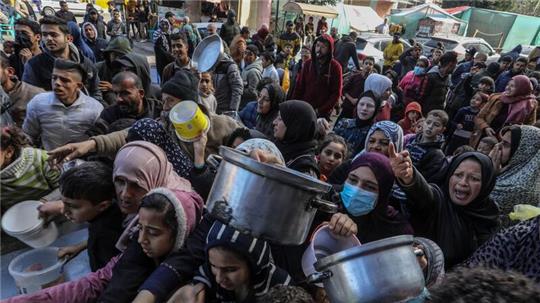 Vertriebene Palästinenser warten in Rafah, im Süden des Gazastreifens, auf Lebensmittel, die von palästinensischen Freiwilligen verteilt werden.