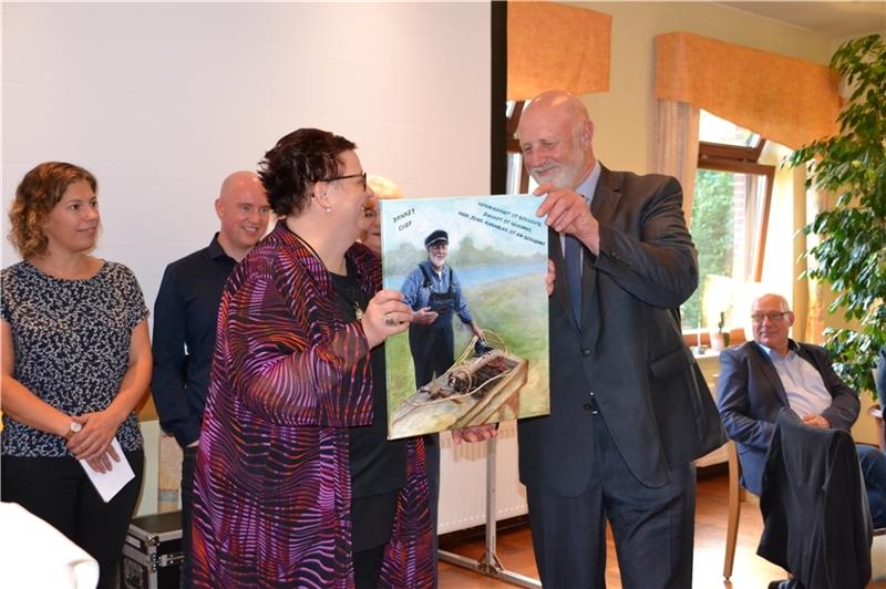 Verwaltungsmitarbeiterin Claudia Rambow überreicht ihrem ehemaligen Chef Edgar Goedecke ein Bild zum verspäteten Abschied . Foto: Helfferich