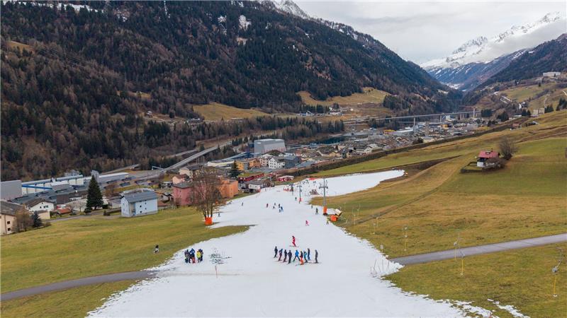 Viel zu warm: Skifahrer fahren auf einer schmalen Piste aus Kunstschnee im Tessin in der Schweiz. 