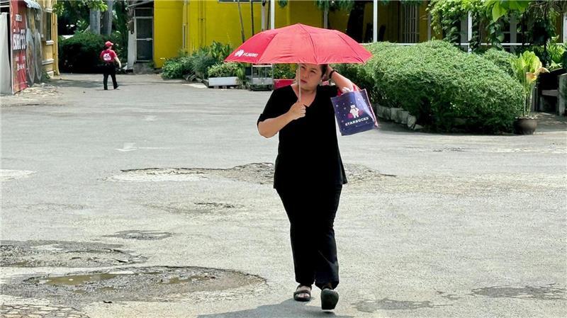 Viele schützen sich mit Schirmen vor der Sonne.