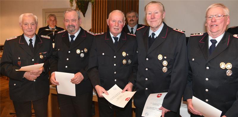 Vize-Kreisbrandmeister Thorsten Hellwege und Gemeindebrandmeister Rolf Jarck (hinten) ehren Feuerwehrmitglieder für 50-jähriges Engagement. Fotos: Beneke