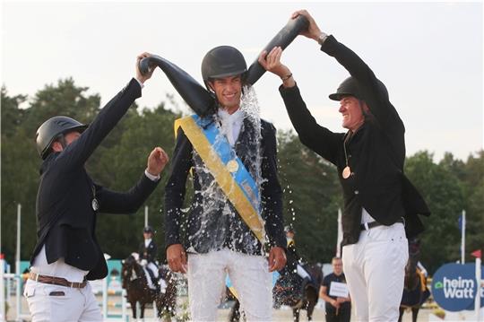 Vizemeister Lennert Hauschild (RV Sittensen, links) und Bronzegewinner Hilmar Meyer (Sportförderung Löwen Classics, rechts) sorgen auf dem Siegerpodest für die Meisterdusche des neuen Landesmeisters René Dittmer. Foto: Tina Pantel/PSV Hannover