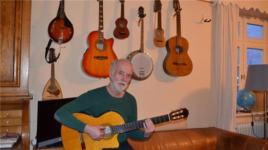 Diakon Volker Austein spielt in seinem Wohnzimmer Gitarre.