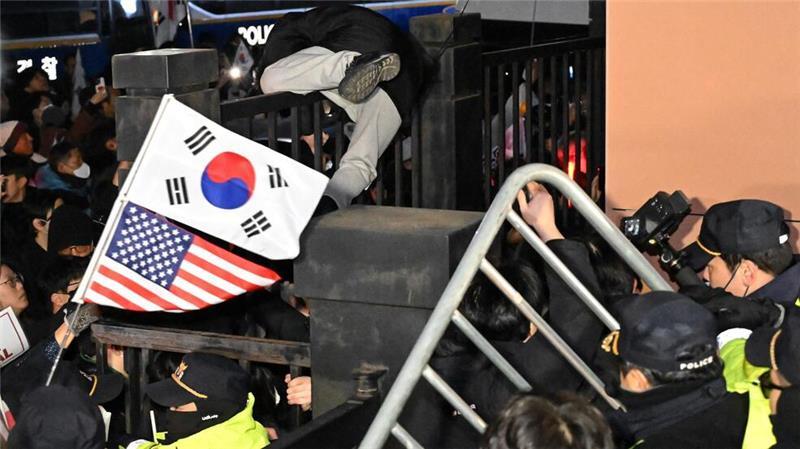 Voller Einsatz für den suspendierten südkoreanischen Präsidenten: Einer seiner Anhänger klettert über eine Mauer, um in das westliche Bezirksgericht zu gelangen, nachdem Yoon formell verhaftet wurde