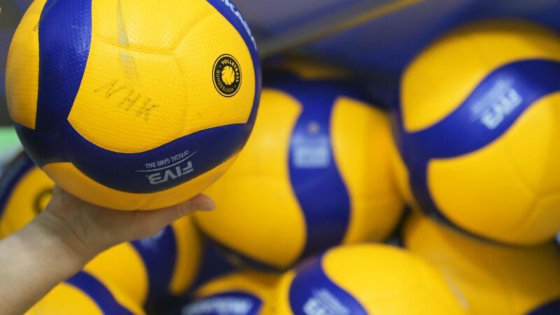 Volleybälle liegen in einer Halle.