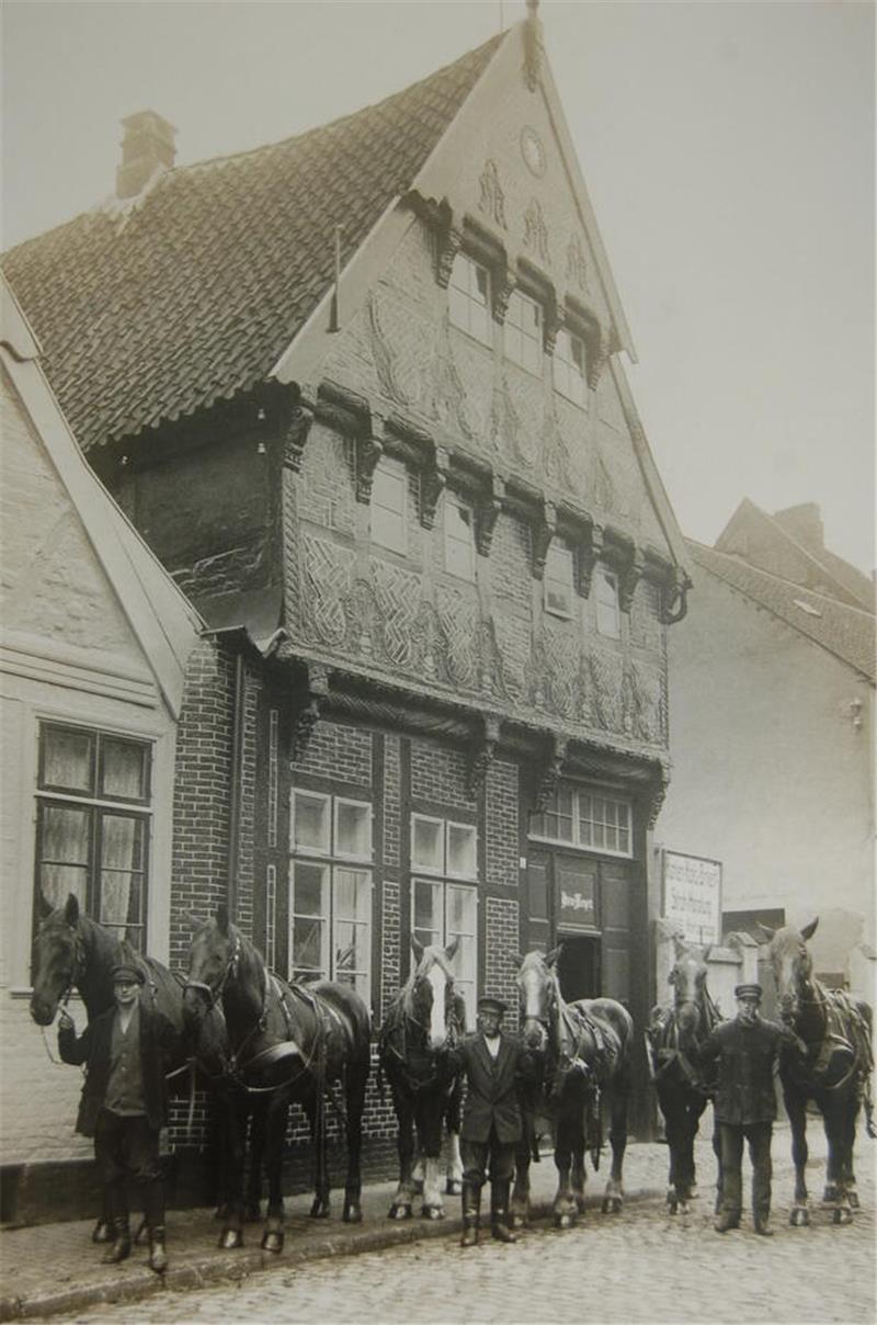 Die Fuhrmänner vom Unternehmen Meyer halten vor dem haus jeweils ein Zwei-Pferdegespann am Zügel