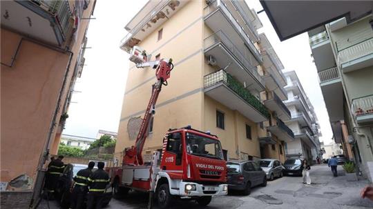 Von einem Hubwagen aus inspiziert ein Feuerwehrmann Schäden an einem Gebäude.