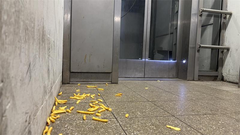 Vor dem Fahrstuhl in der Unterführung liegen Pommes auf dem Boden.