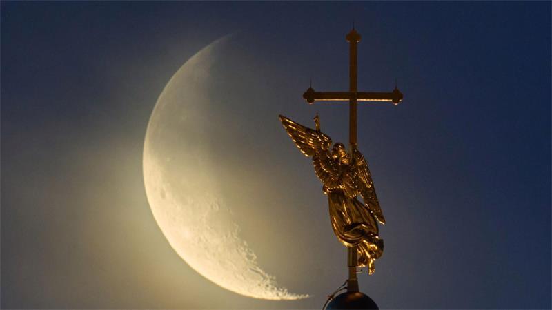 Vor dem Mond ist das Wahrzeichen der Stadt St. Petersburg, eine Wetterfahne in Form eines Engels, zu sehen.