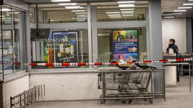 Tödliche Schüsse in Supermarkt - Kassiererin stirbt Vor dem Supermarkt hat die Polizei Absperrband angebracht.