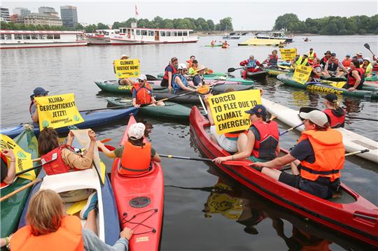 Vor dem Weltflüchtlingstag am Dienstag demonstrieren Mitglieder von Greenpeace und Fridays for Future mit Kajaks, Schlauchbooten und Bannern auf der Binnenalster in Hamburg.  Foto: Bodo Marks/dpa