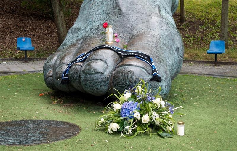 Vor der Bronzestatue, die den Fuß von Uwe Seeler darstellen soll, liegen Blumen. Foto: Daniel Bockwoldt/dpa