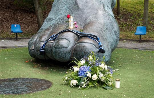 Vor der Bronzestatue, die den Fuß von Uwe Seeler darstellen soll, liegen Blumen. Foto: Daniel Bockwoldt/dpa