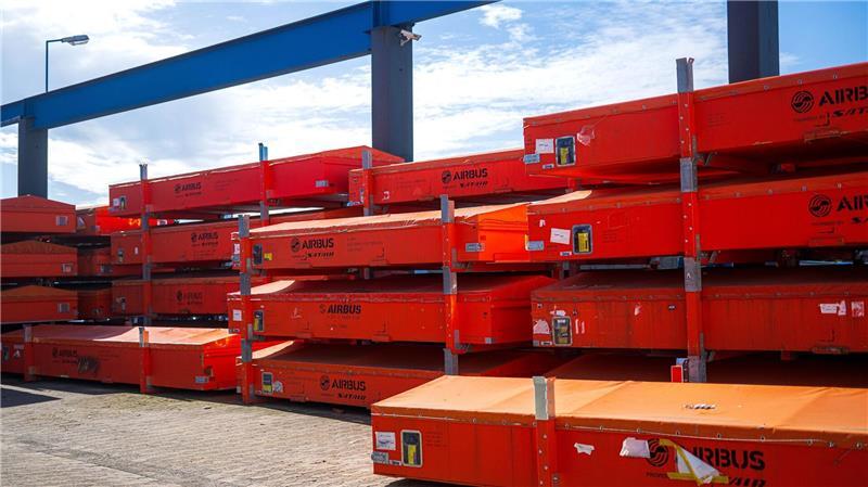 Vor der Werkhalle warten beschädigte Fahrzeugteile auf die Reparatur.