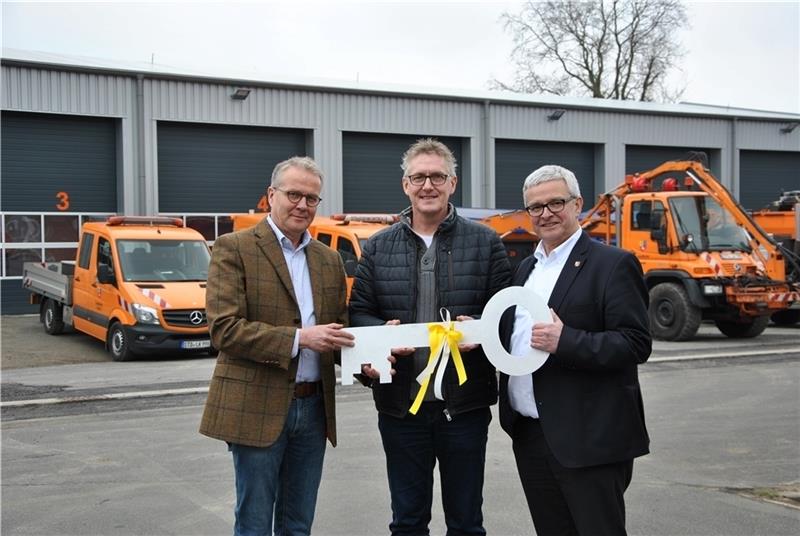 Vor der neuen Fahrzeug- und Werkstatthalle und den Einsatzfahrzeugen: Einen symbolischen Schlüssel überreichen Landrat Michael Roesberg (rechts) und Architekt Gerd Wichers (links) dem Leiter der Straßenmeisterei, Uwe Pahl. Foto: Lohmann