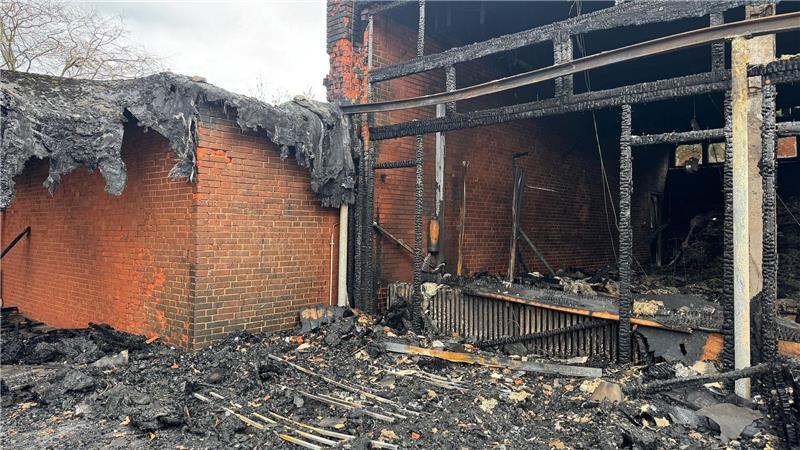 Vor der zerstörten Aula zeigt sich das Ausmaß des Brandes deutlich.