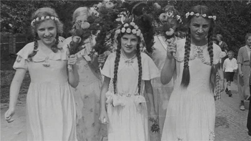 Junge Mädchen mit Kleid und Blumenkränzen marschieren mit beim Schützenfest in Steinkirchen vor rund 90 Jahren.