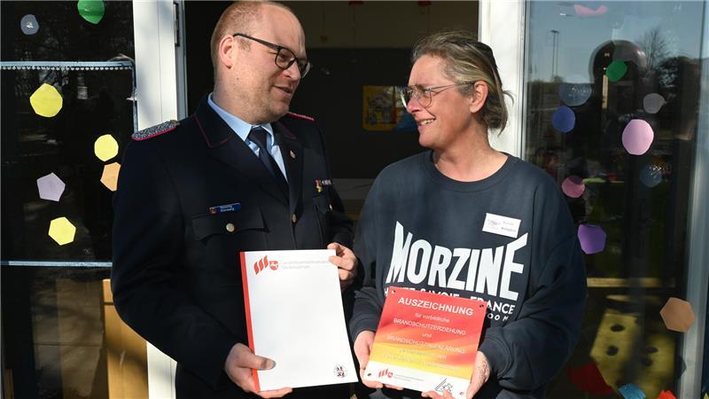 Vorbildliche Brandschutzerziehung: Kreisbrandmeister Henning Klensang überreicht Urkunde und Plakette an Karina Klingbeil von der Kita An der Este in Estebrügge.