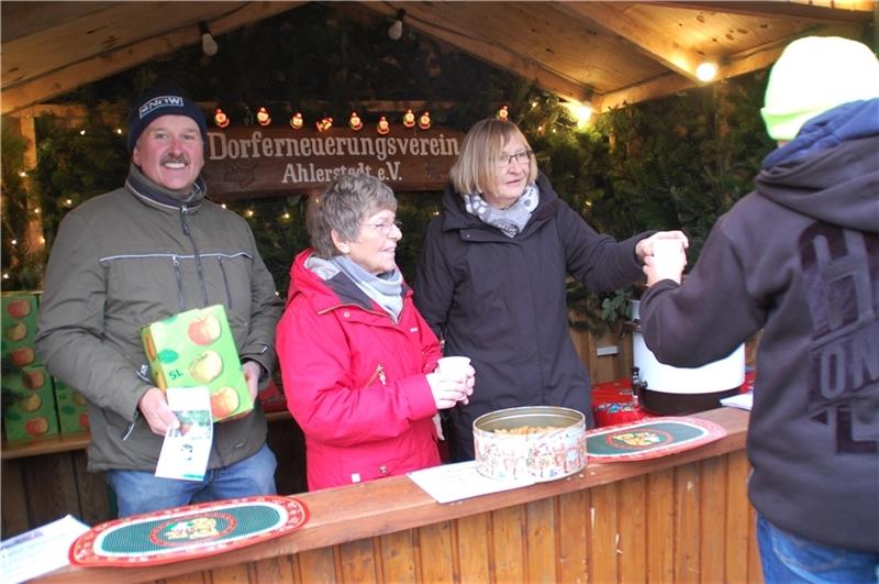 Vorsitzender Volkhard Treisch (von links), Jutta Rieper und Gudrun Zühlke verkaufen Apfelpunsch aus eigener Ernte für die Projekte des Dorferneuerungsvereins Ahlerstedt. Foto: Laudien