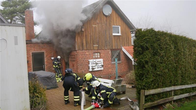 Scheune brennt in Hemmoor - Eine Person verletzt Während der Rauch aus der Scheune quillt, versuchen die Einsatzkräfte, mit mehreren Schläuchen das Feuer einzudämmen. Foto: Lange