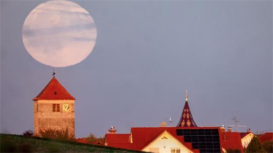 Während der Römerturm in Emerkingen von der Abendsonne angestrahlt wird, geht hinter ihm der Vollmond auf.