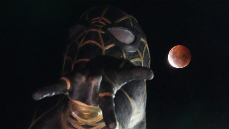 Wolken nehmen Sicht auf partielle Mondfinsternis Während der partiellen Mondfinsternis geht in El Alto, Bolivien, der Mond hinter einer Spider-Man-Statue auf.