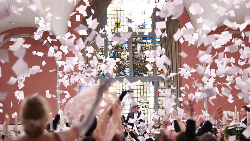 Während des Festmahls wird mit Papier geworfen und Geld für einen guten Zweck eingesammelt.