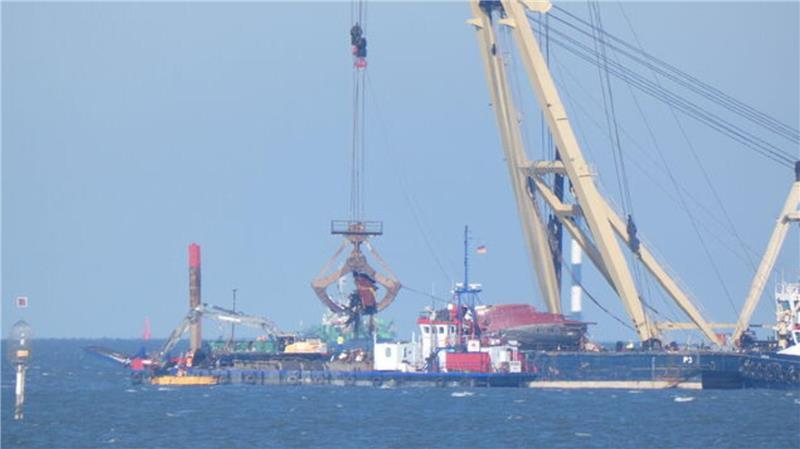 Während ein Teil des Schiffsrumpfs der "Ethel von Brixham" bereits auf dem Ponton des Schwimmkrans "Enak" liegt, befinden sich in der Schaufel deutlich sichtbar weitere Planken.