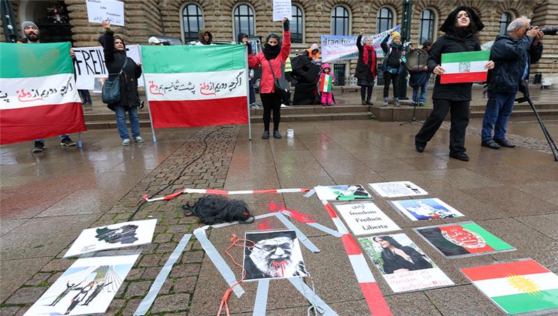 Warum sich Frauen in Hamburg öffentlich die Haare abschneiden Während einer Demonstration gegen das politische Regime im Iran liegen Plakate und eine Perücke mit roter Farbe auf dem Rathausplatz. Foto: Bodo Marks/dpa