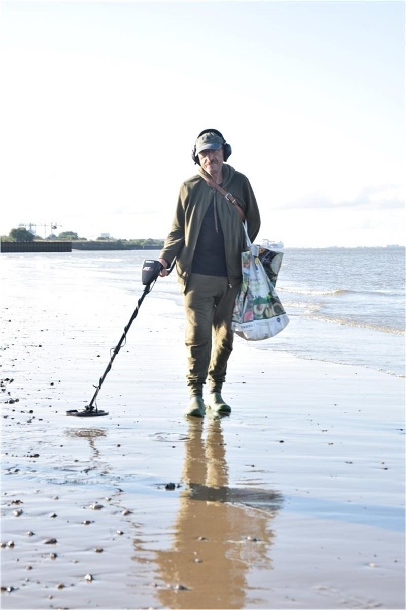 Waldemar Fecsch aus Hamburg mit einem Metalldetektor am Strand.