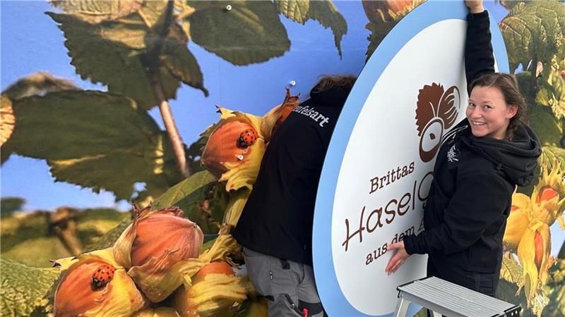 Altländerin ist Pionierin beim Haselnussanbau – Manufaktur eröffnet Wand der Nussmanufaktur: Das Werbeschild für Brittas HaselGenuss wird von der Agentur Teufelsart an der Alten Sparkasse in Mittelnkirchen montiert.