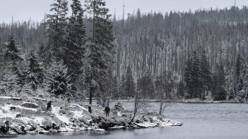 Winterwetter in Deutschland mit Schnee und Kälte Wanderer gehen am leicht verschneiten Oderteich im Harz spazieren.