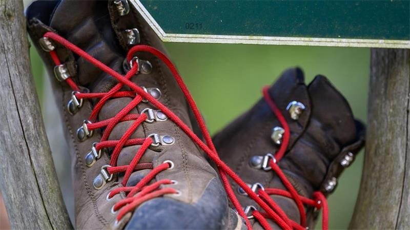 Wanderweg als Wirtschaftsmotor: Wie Gäste umworben werden Wanderschuhe stehen in einem Wegweiser am Fuß des Fichtelbergs.
