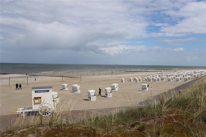 Die schönsten Inseln des Wattenmeers Wangerooge: Zwischen den zahlreichen Strandkörben gehen einige Besucher spazieren. Foto: Peter Kuchenbuch-Hanken/dpa +++ dpa-Bildfunk +++