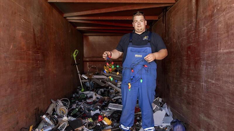 Was die Leute so alles entsorgen: Mitarbeiter Nicolai Hustedt hält im Container für Elektroschrott eine bunte Lichterkette in die Höhe.