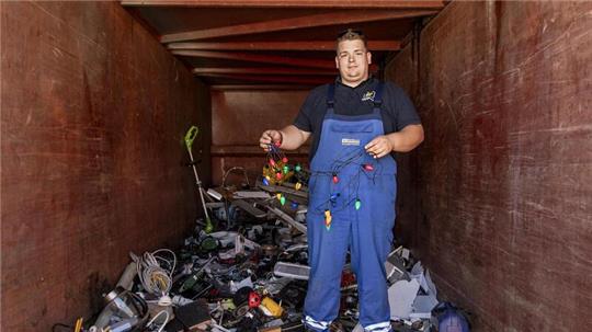 Was die Leute so alles entsorgen: Mitarbeiter Nicolai Hustedt hält im Container für Elektroschrott eine bunte Lichterkette in die Höhe.