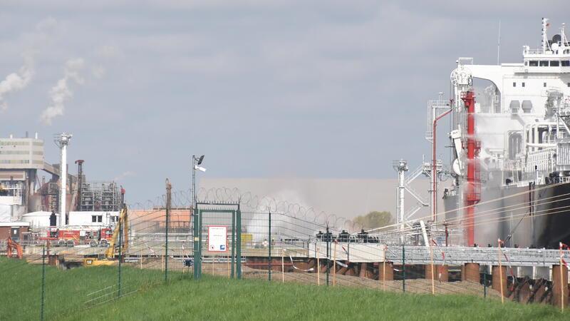 Wasserwerfer marsch: Blick vom Schwinge-Deich auf den Industriehafen in Stade-Bützfleth und das schwimmende LNG-Terminal Energos Force, links steht die Feuerwehr.