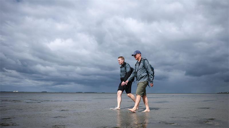 Hautnahe Naturerfahrung für Spitzenpolitiker im Watt Wattwanderung vor dramatischer Wolkenkulisse.