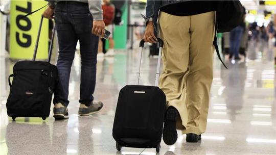 Ein Mann und eine Frau ziehen an einem Flughafen ihre Koffer.