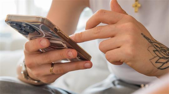 Eine Frau hält ein Smartphone in der Hand.