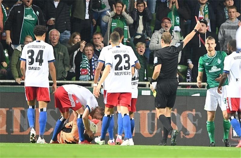 Werders Christian Gross (rechts) bekommt von Schiedsrichter Sascha Stegemann nach einem Foul an Hamburgs Torwart Daniel Heuer Fernandes die Roten Karte. Foto: Carmen Jaspersen/dpa