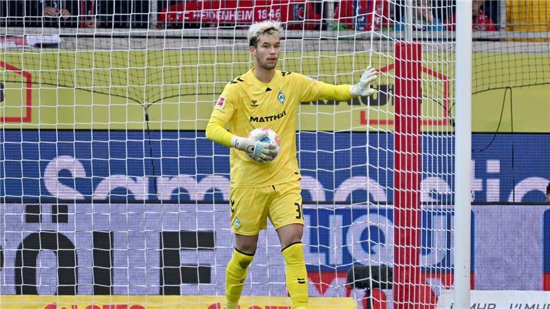 Werders Torwart Mio Backhaus steht mit dem Ball im Tor. 