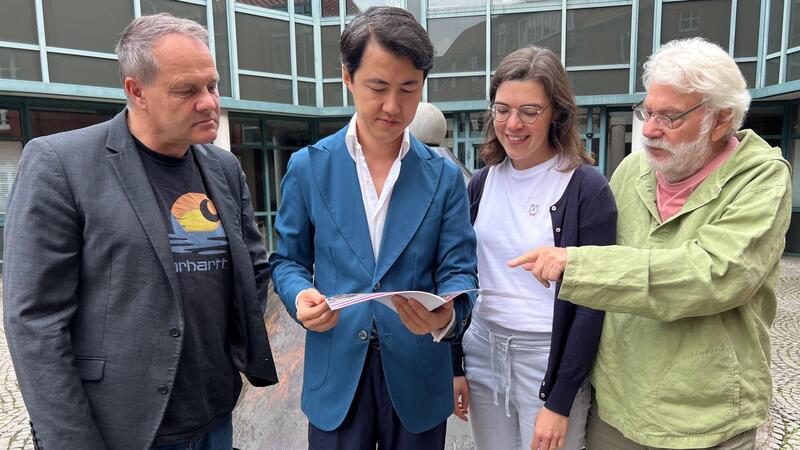 Werfen einen Blick ins Programm des IMF (von links): Dr. Andreas Schäfer, Haiou Zhang, Lena Zimmer und Dieter Klar vor dem Stader Rathaus.