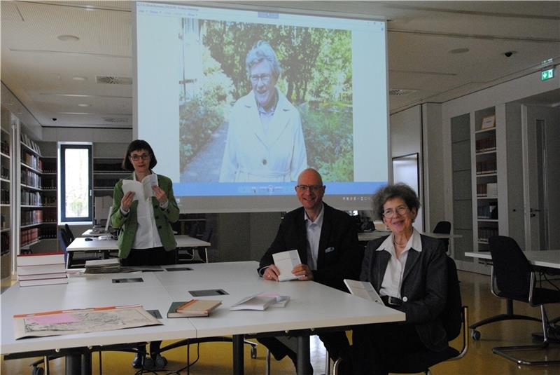 Werfen einen Blick ins neue Stader Jahrbuch , das Elfriede Bachmann (auf der Leinwand im Hintergrund) gewidmet ist und an dem sie entscheidend mitgearbeitet haben: (von links) Dr. Gudrun Fiedler, Arend Mindermann und Ida-Christine Riggert-M
