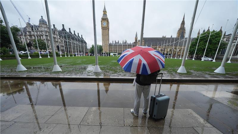 Wetter in Großbritannien: Ein Passant trägt einen Regenschirm auf dem Parliament Square in Westminster im Zentrum Londons. 